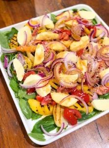 Char-grilled peach salad with basil, bocconcini, cherry tomatoes, and pomegranate molasses dressing.