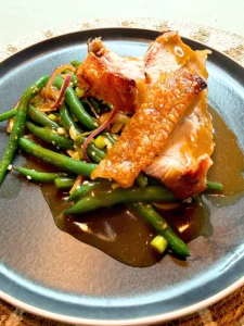 Crispy BBQ roast pork with golden crackling paired with an Asian-inspired green bean salad, a fresh summer BBQ recipe.